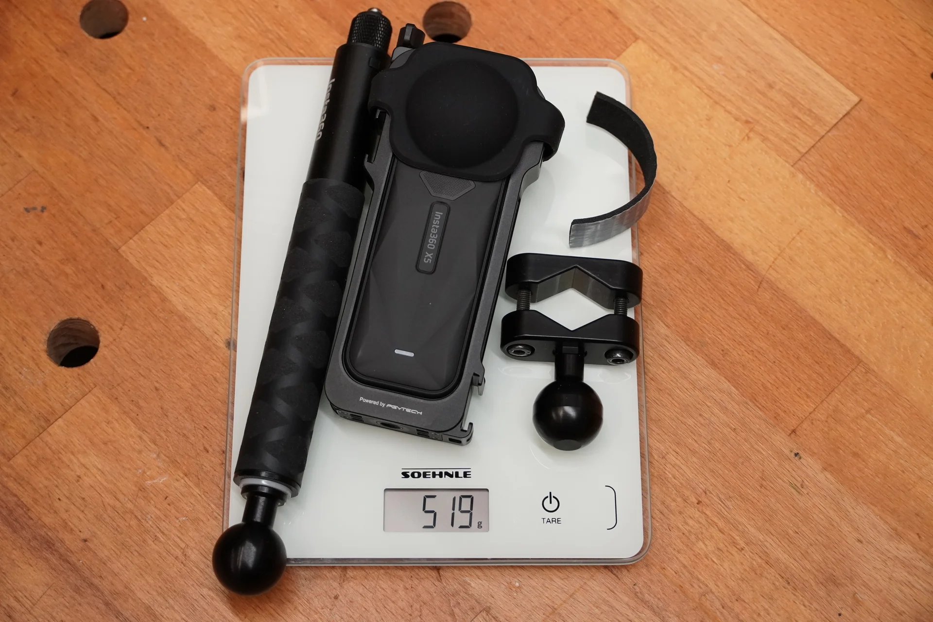 Insta360 X5, Teleskopstab und Kugelflex-Klemmschelle auf einer Digitalwaage mit angezeigten 519 Gramm.